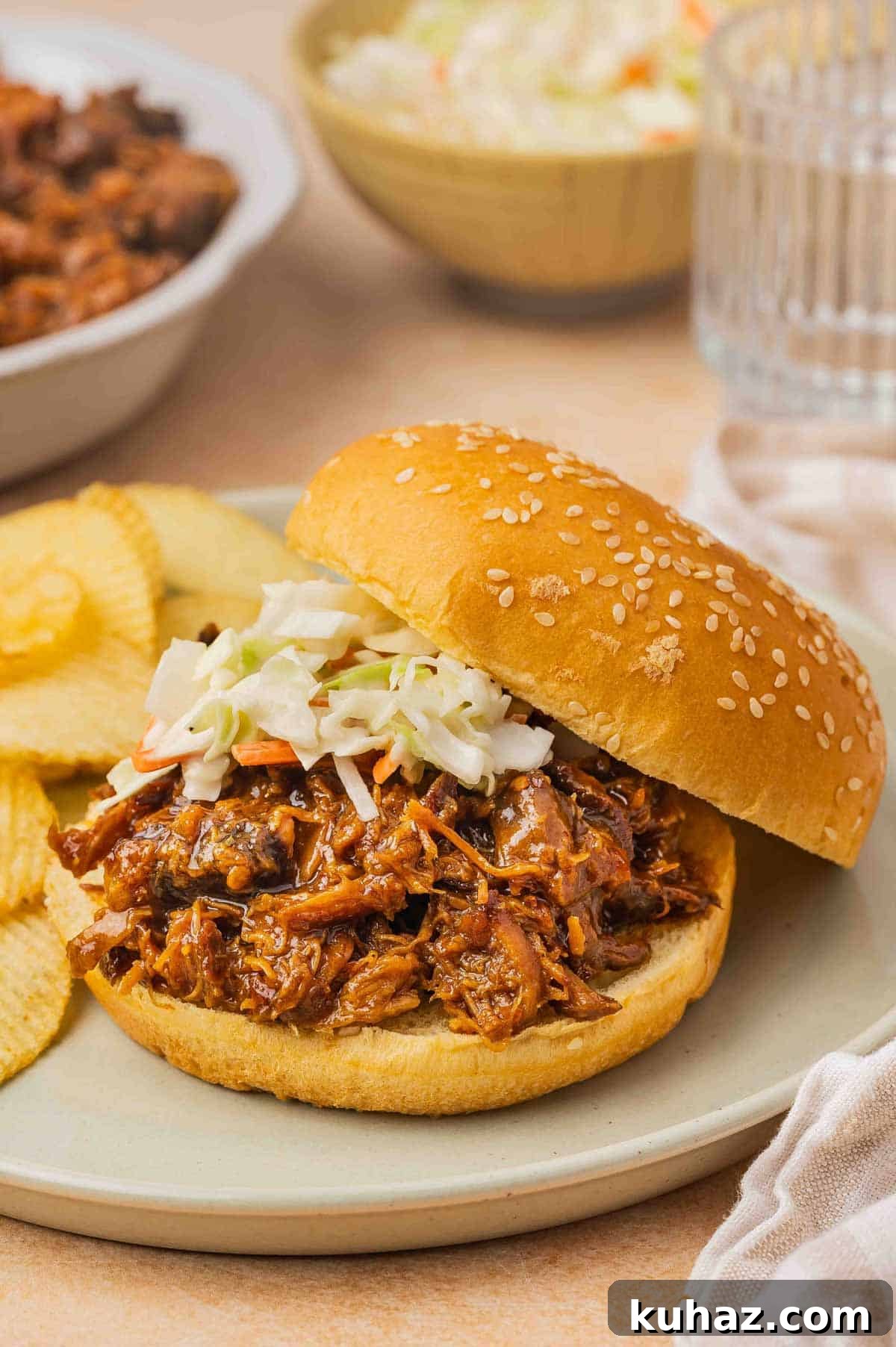 A plate with slow cooker hot honey chicken on a burger bun with coleslaw on top.