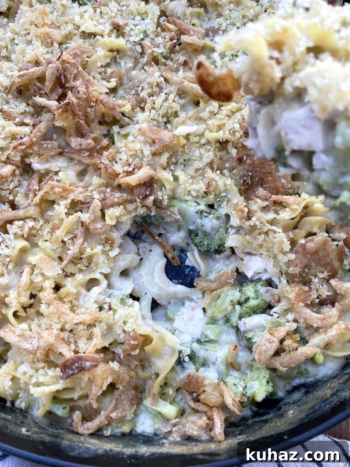 A scoop of cheesy chicken noodle casserole being served and the inside of the casserole.