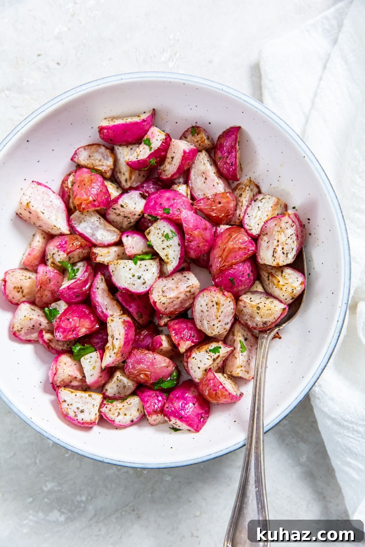 Crispy Air Fryer Radishes with Garlic and Parmesan 2 Air Fyer radishes in a white bowl with a spoon in it and a white napkin on the side