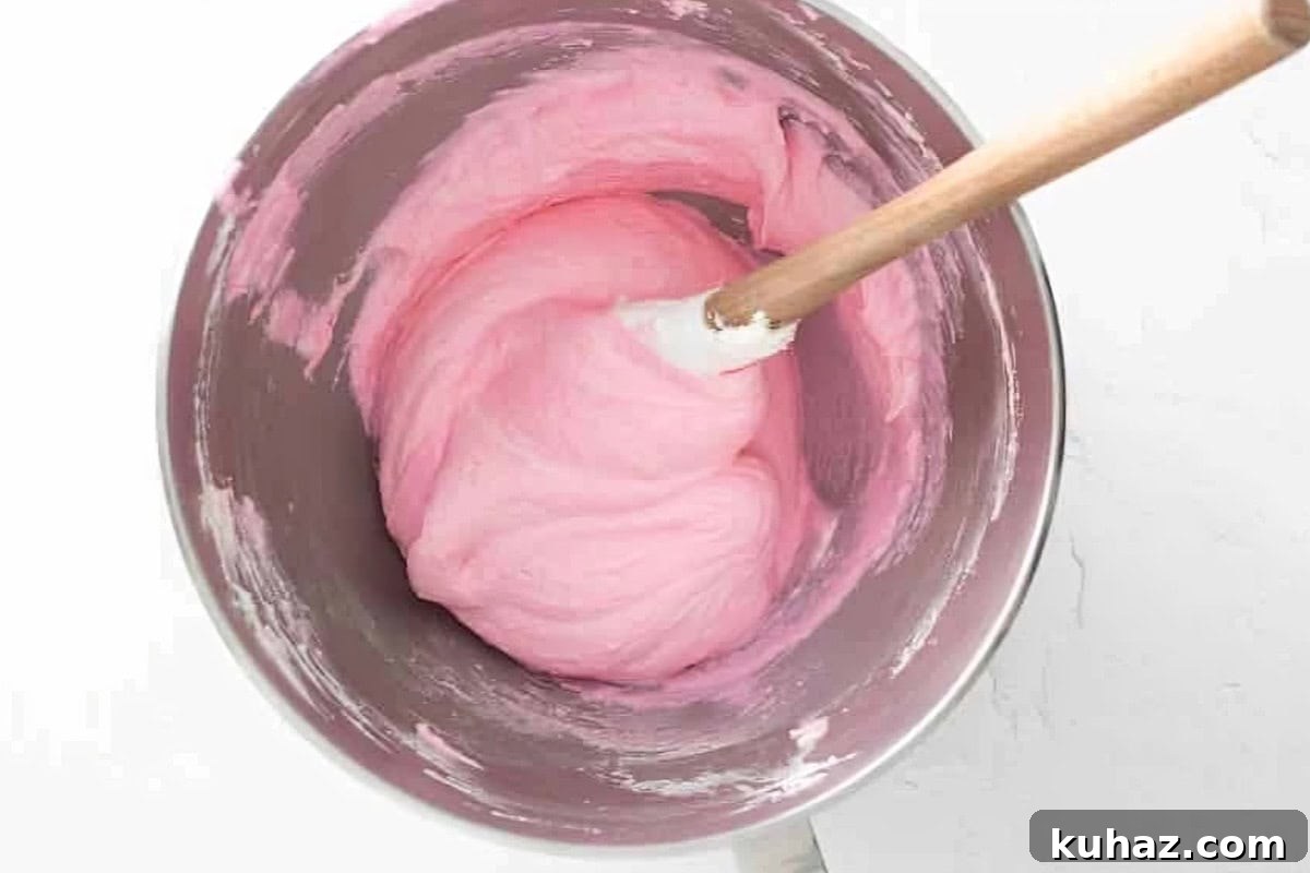 Valentine's Day Macarons: Romantic Recipes and Decorating Ideas 6 pink macaron batter in a stainless mixing bowl with a rubber spatula.