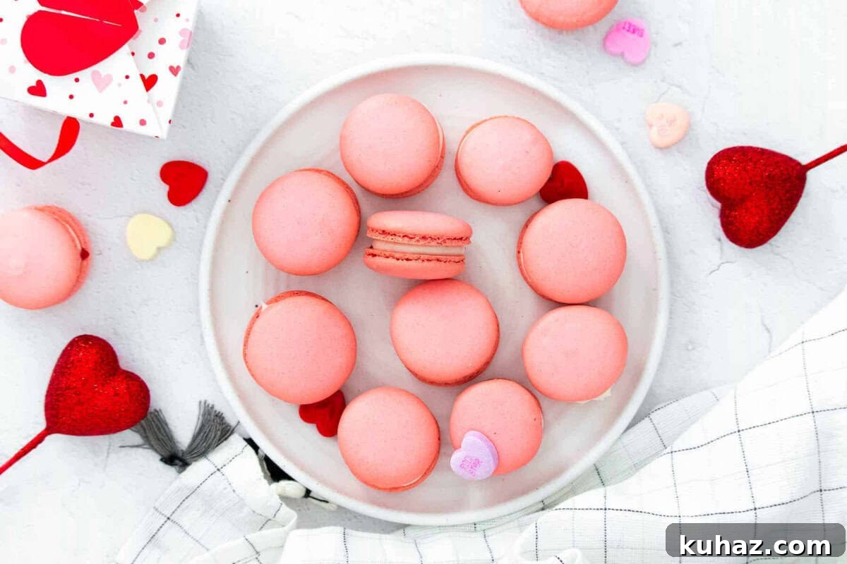 Valentine's Day Macarons: Romantic Recipes and Decorating Ideas 3 overhead view of pink macarons on a plate surrounded by Valentine's Day decor.