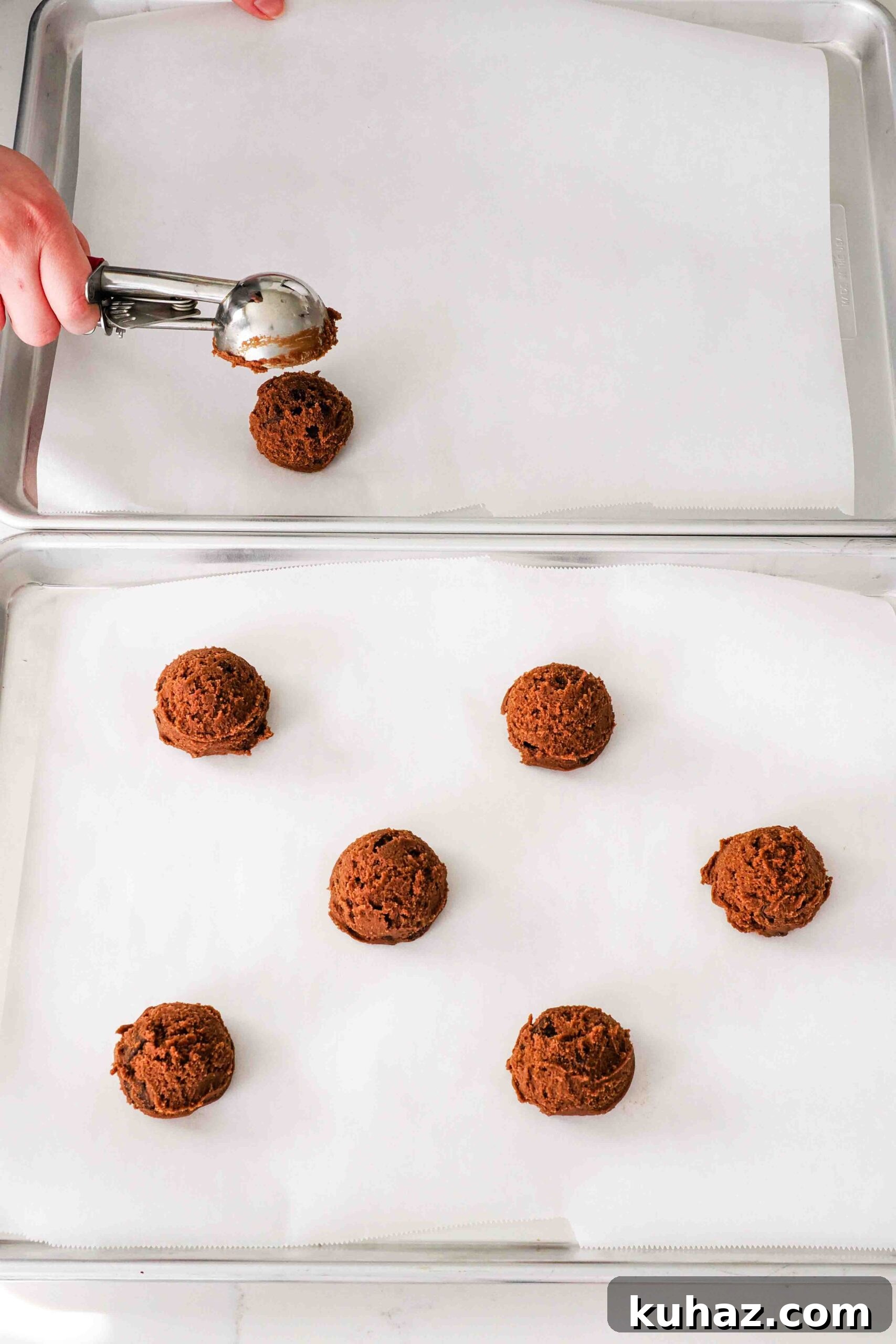 Chewy Double Chocolate Chip Cookies Recipe 10 A hand scoops 2" balls of chocolate cookie dough onto parchment-lined baking sheets.