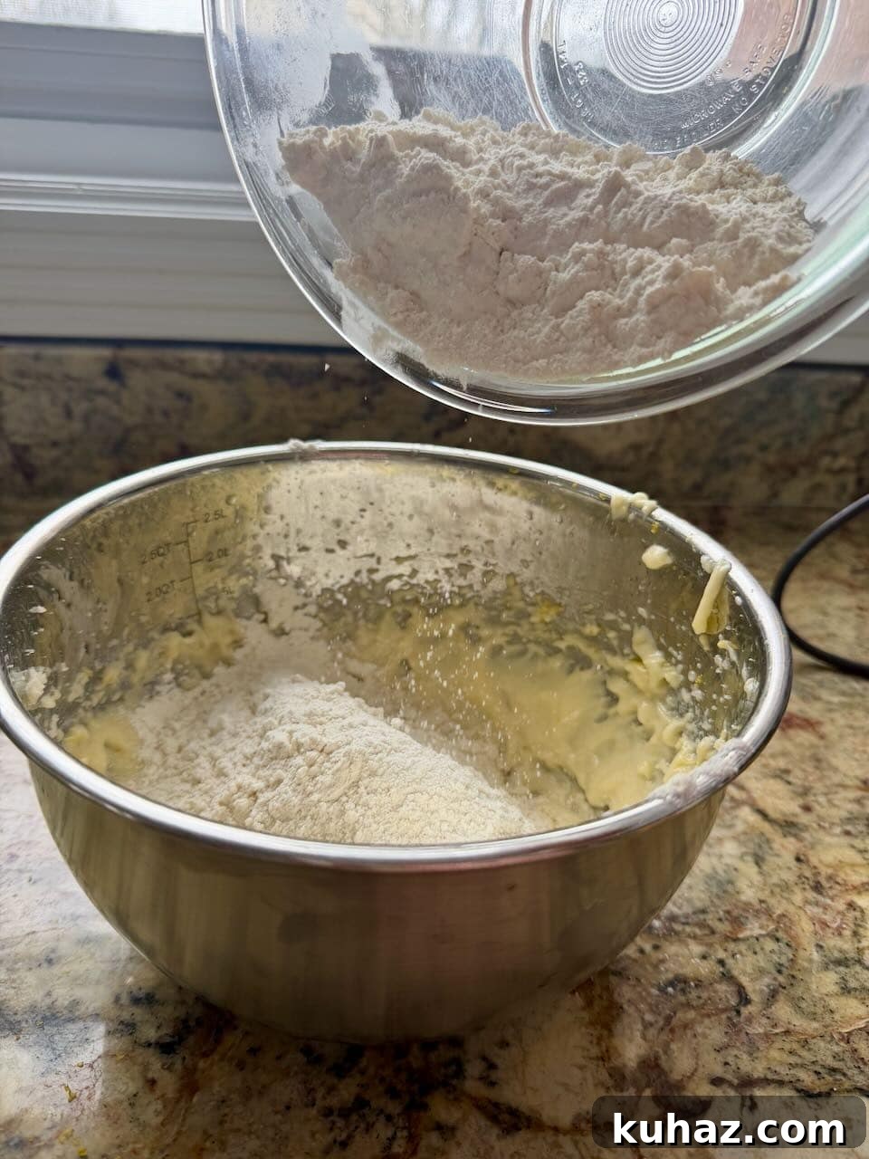 Lemon Crinkle Cookies Made with Sourdough Discard 7 Dry ingredients being poured into the lemon cookie dough mixture in a mixing bowl.