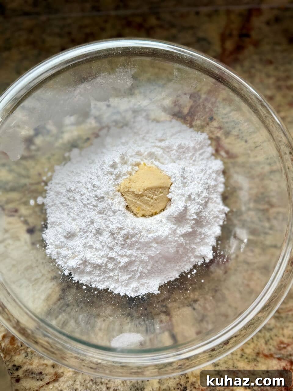 Lemon Crinkle Cookies Made with Sourdough Discard 8 Lemon cookie dough ball placed in powdered sugar for coating before baking.