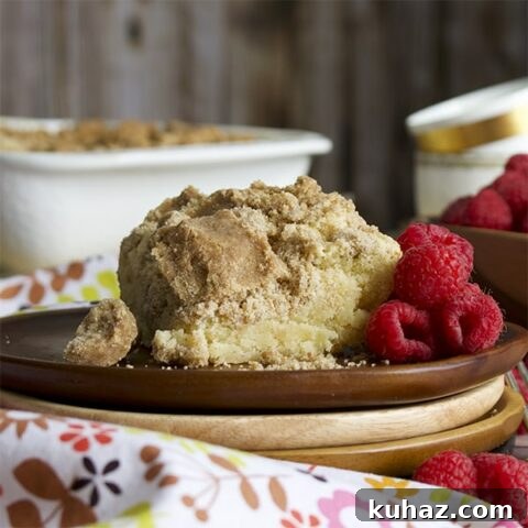A slice of crumb cake on a plate with raspberries.