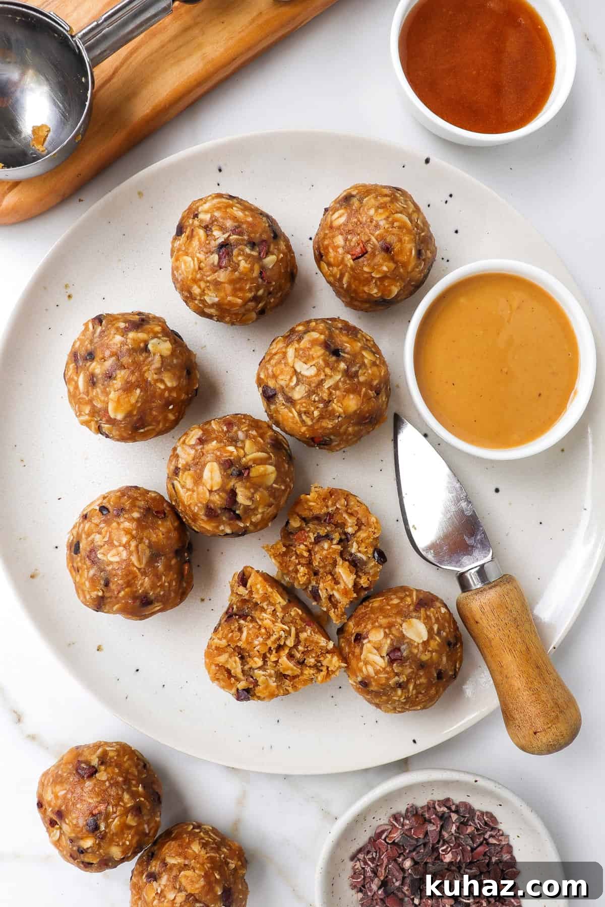 No-Bake Peanut Butter Bliss Balls: Protein-Packed Bites 2 Bliss balls on a plate with a knife and dish of peanut butter.