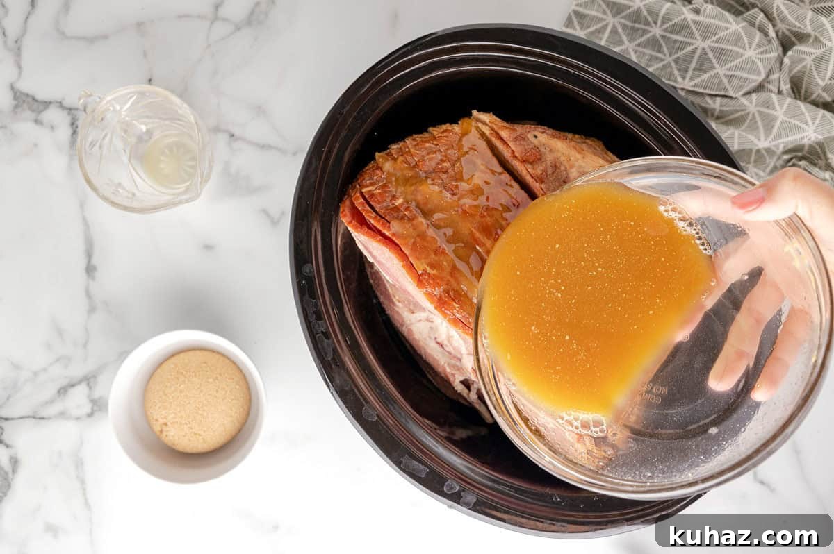 sauce being poured over spiral ham in crockpot