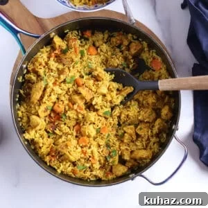 Moroccan Chicken with Saffron Rice 6 A deep skillet on a wooden board with a spoon lifting some chicken and rice in it.