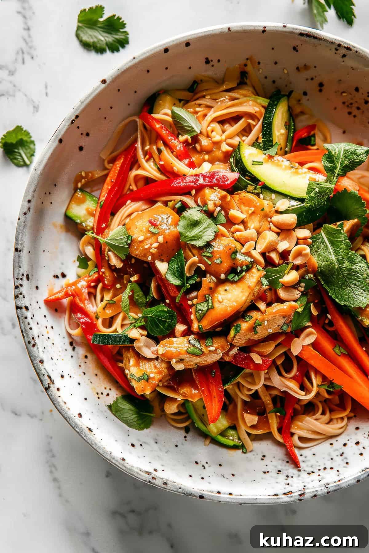 Easy bang bang noodles with chicken and peanuts in a white bowl.