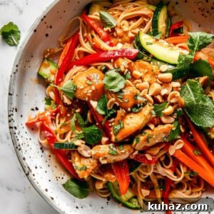 Easy bang bang noodles with chicken and peanuts in a white bowl.