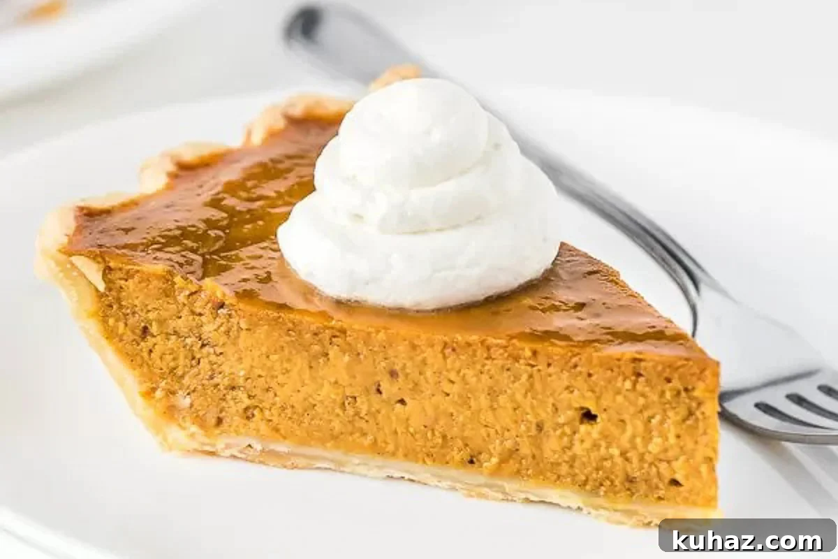 Classic Creamy Pumpkin Pie with Flaky Crust 2 A slice of Pumpkin pie topped with whipped cream on a plate