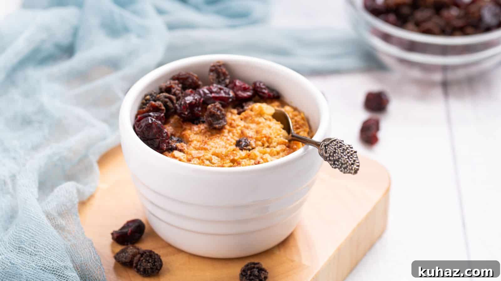 13 Gluten-Free Breakfast Recipes to Kickstart Your Morning 14 A bowl of baked oatmeal topped with raisins on a wooden table, accompanied by a blue cloth and spoon.