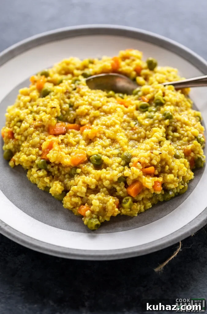 Instant Pot Vegetable Daliya Recipe (Broken Wheat Khichdi) 2 vegetable daliya served on a white plate with spoon on the side