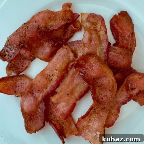 A plate of crispy, perfectly cooked air fryer bacon, highlighting its texture and seasoning.