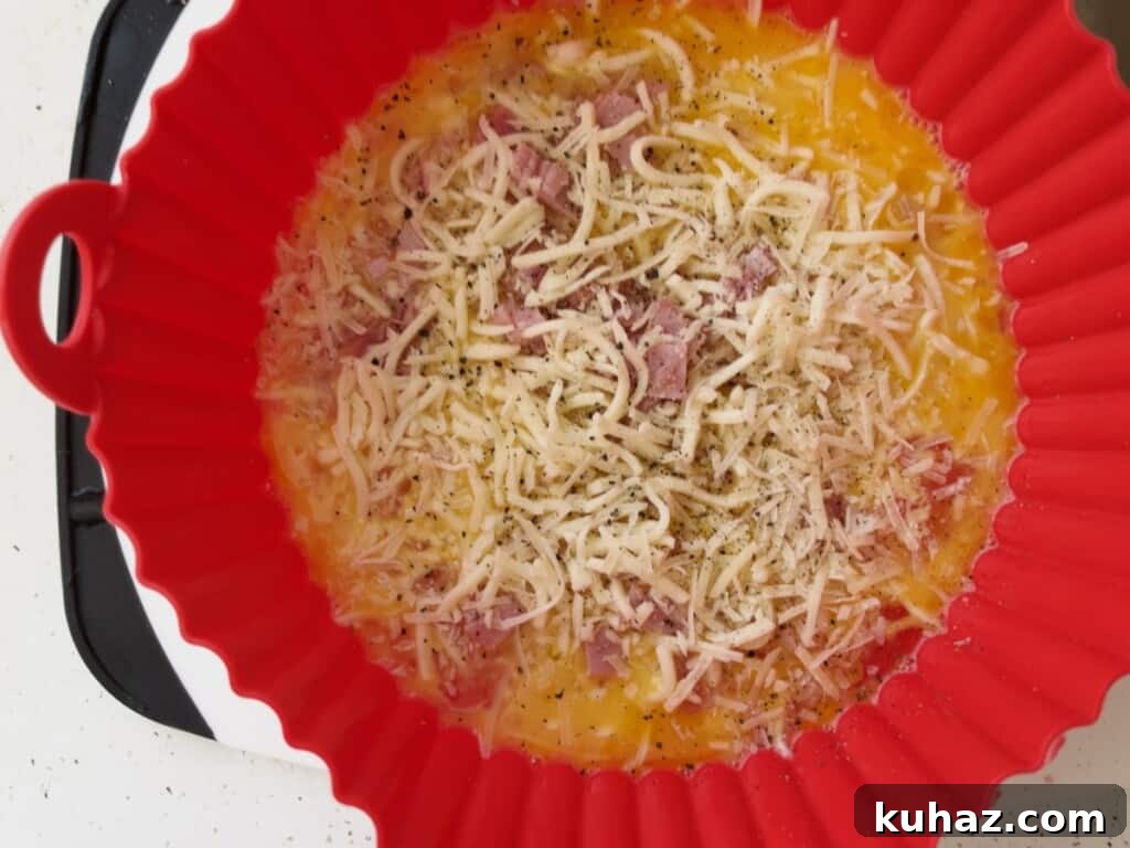 Air Fryer Ham and Cheese Omelet 5 preparing air fryer ham and cheese omelet and adding ham and cheese to scrambled eggs