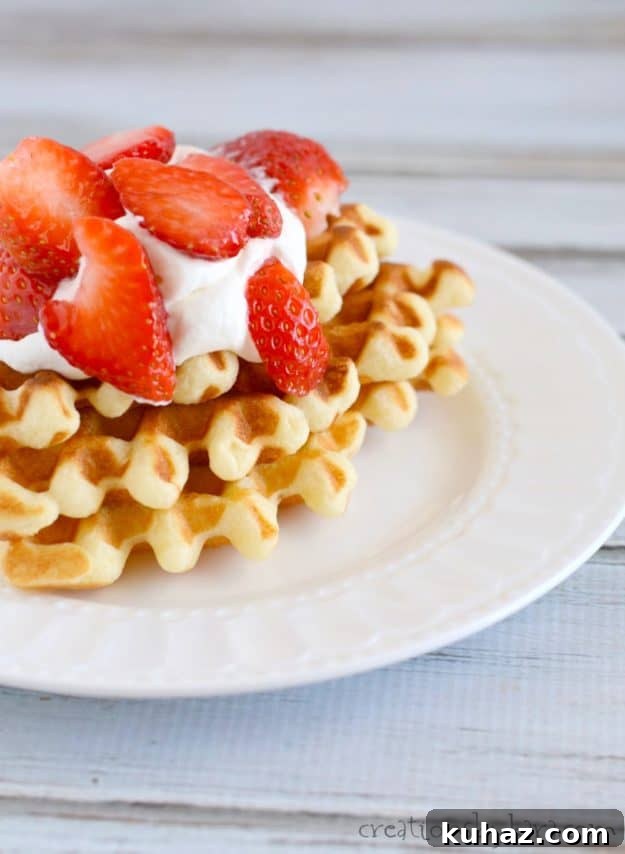 plate of waffles with whipped cream and strawberries