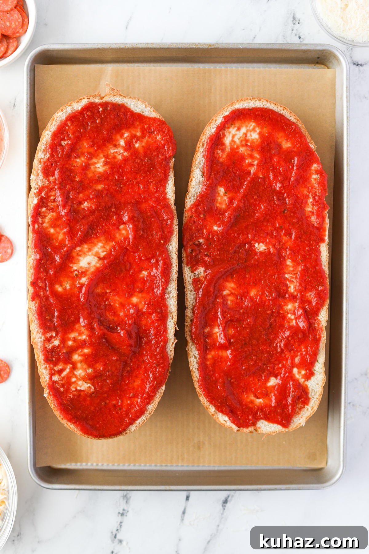 Homemade French Bread Pizza Recipe 5 Spreading pizza sauce on French bread halves.