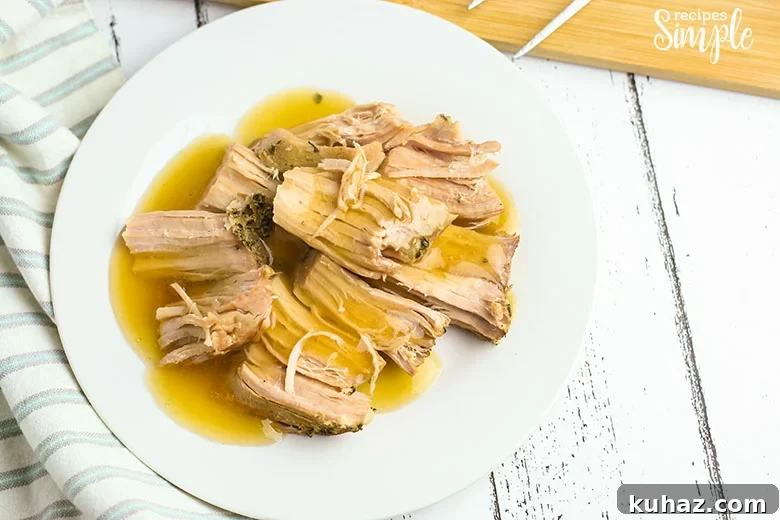 Slow Cooker Pork Tenderloin with Savory Gravy 3 Pork Tenderloin on white plate with gravy poured over it.