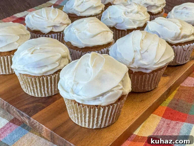 Pumpkin Spice Cupcake Recipe with Cream Cheese Frosting 2 Cream cheese frosting on top of three ingredient pumpkin spice latte flavored cupcakes on a wooden board on a plaid napkin.