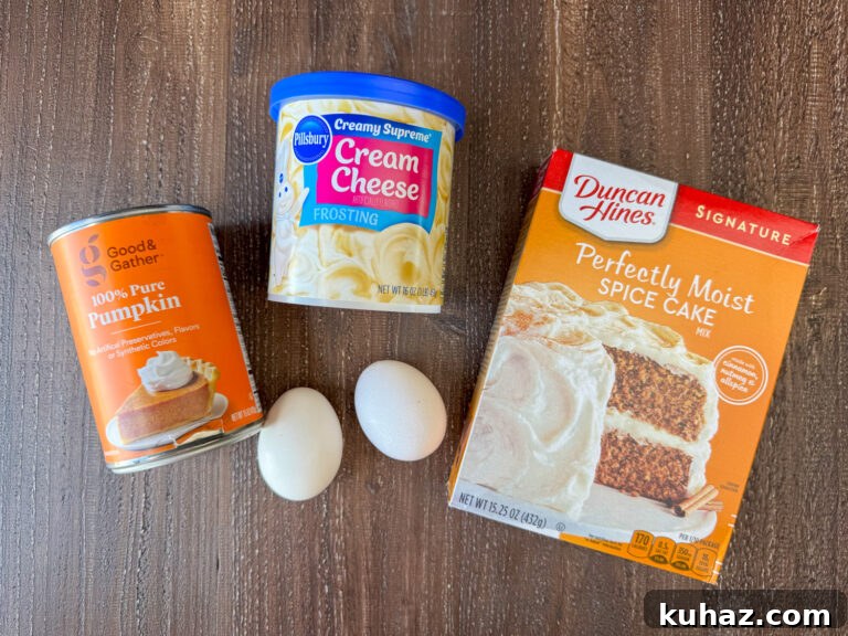 Pumpkin Spice Cupcake Recipe with Cream Cheese Frosting 4 Ingredients to make Pumpkin Spice Cupcakes are a can of pure pumpkin, a box of spice cake mix, eggs and a can of cream cheese frosting on a wooden counter top.