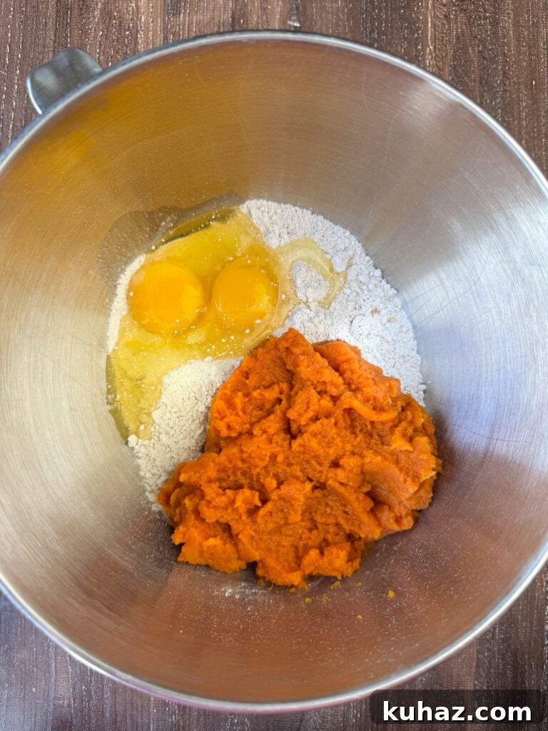 Pumpkin Spice Cupcake Recipe with Cream Cheese Frosting 5 Box of spice cake mix in a silver mixing bowl with a can of pureed pumpkin and eggs ready to mix in.