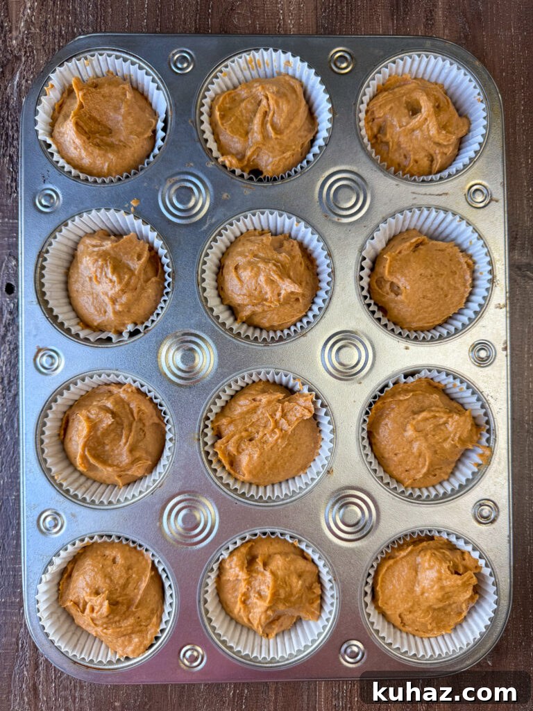 Pumpkin Spice Cupcake Recipe with Cream Cheese Frosting 6 Pumpkin cupcake batter dropped sloppily in liners in a muffin tin.
