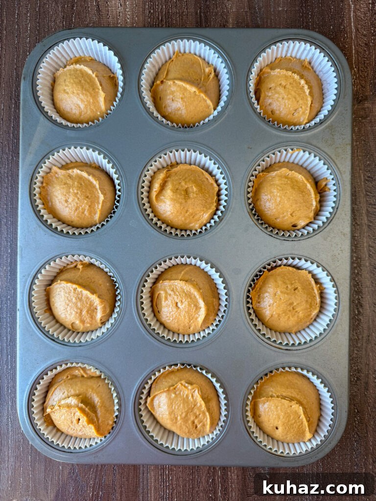 Pumpkin Spice Cupcake Recipe with Cream Cheese Frosting 7 Ice cream scoop used to drop smooth spoonfuls of spiced pumpkin cupcake batter into a muffin with with liners.
