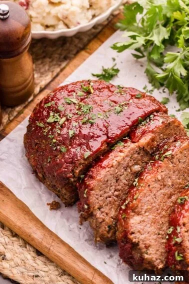 How to Grill Tender Elk Steaks with Smoky Flavor 8 Sliced bison meatloaf with tomato glaze and chopped herbs on parchment paper, with parsley and a pepper grinder in the background.