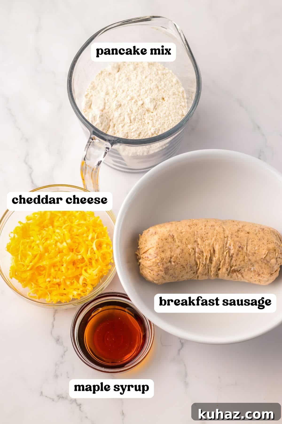 Savory Breakfast Sausage Pancake Muffins 4 Four labeled ingredients for sausage pancake muffins: pancake mix, cheddar cheese, breakfast sausage, and maple syrup.