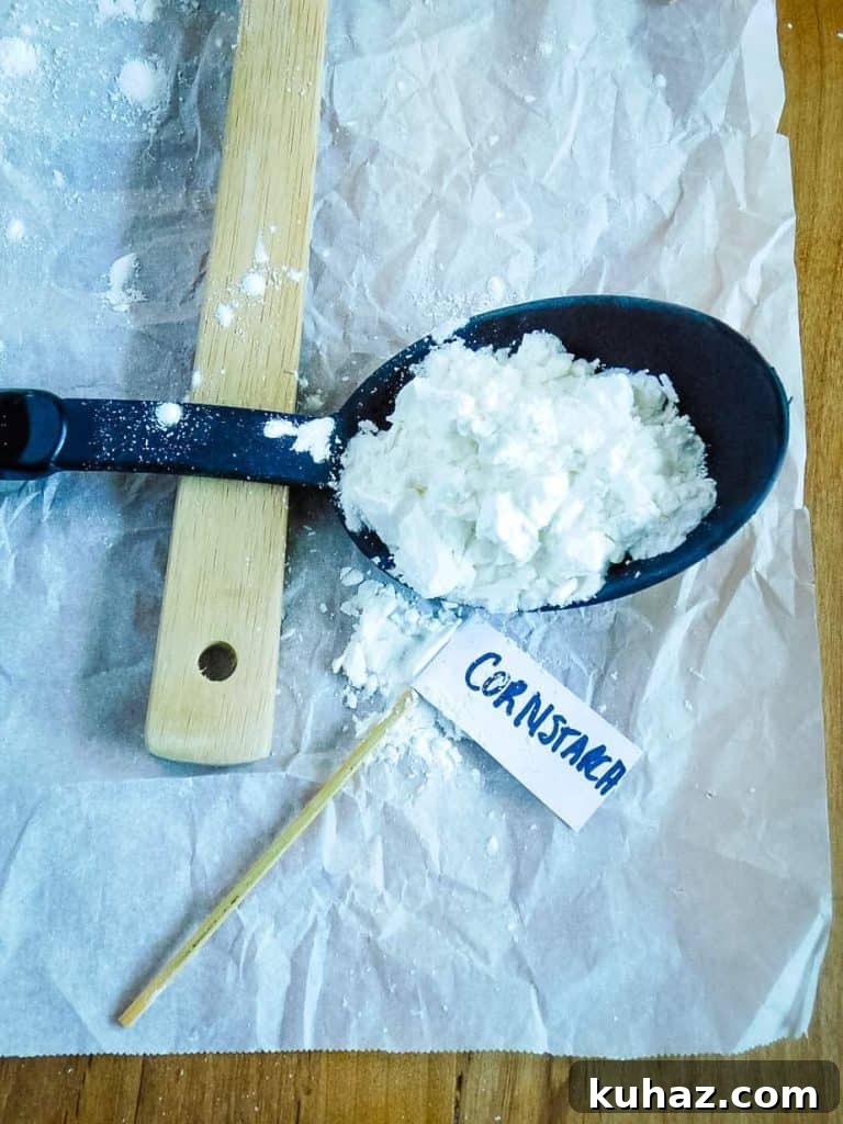 Cornstarch, Tapioca, Arrowroot Compared: Uses and Substitutes 4 Cornstarch on a black spoon