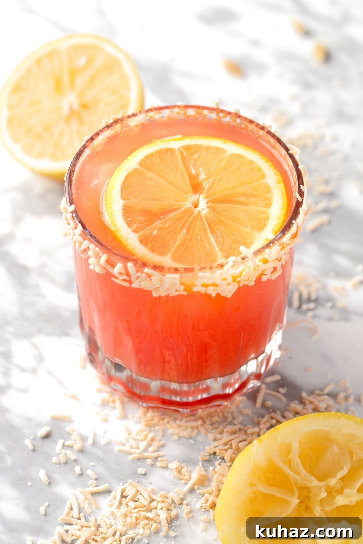 Sparkling Guava Mocktail Recipe with Lime and Mint 2 A guava mocktail garnished with a lemon slice and a coconut rim.