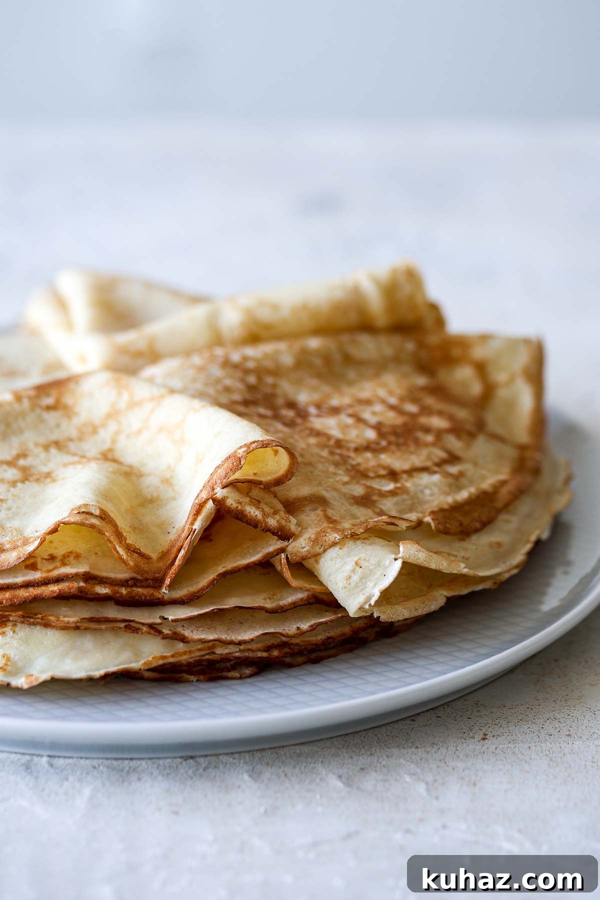 How to Make Sourdough Discard Crepes 14 A stack of sourdough discard crepes with crispy edges on a plate.