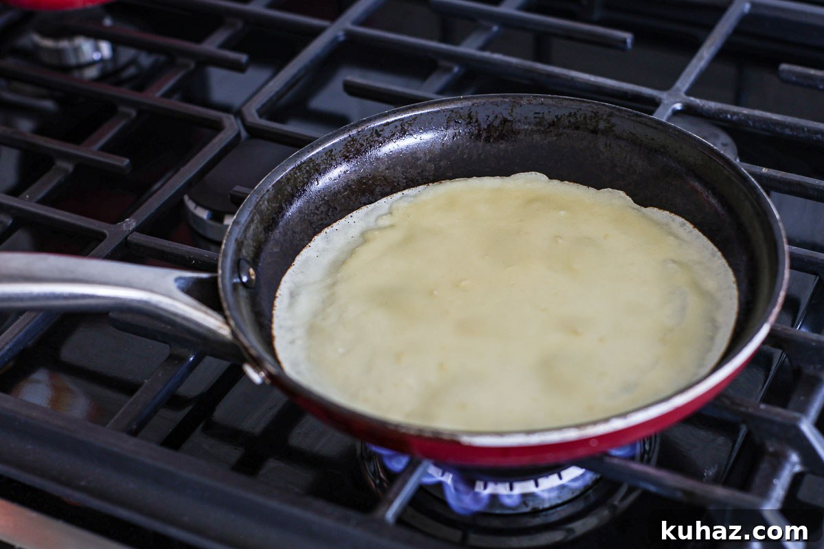 How to Make Sourdough Discard Crepes 7 Crepe cooking on a frying pan.