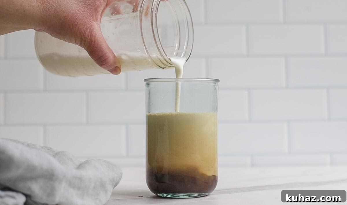 How to Make Sweet Cream Cold Foam at Home 7 pouring cold foam on top of coffee in a glass.