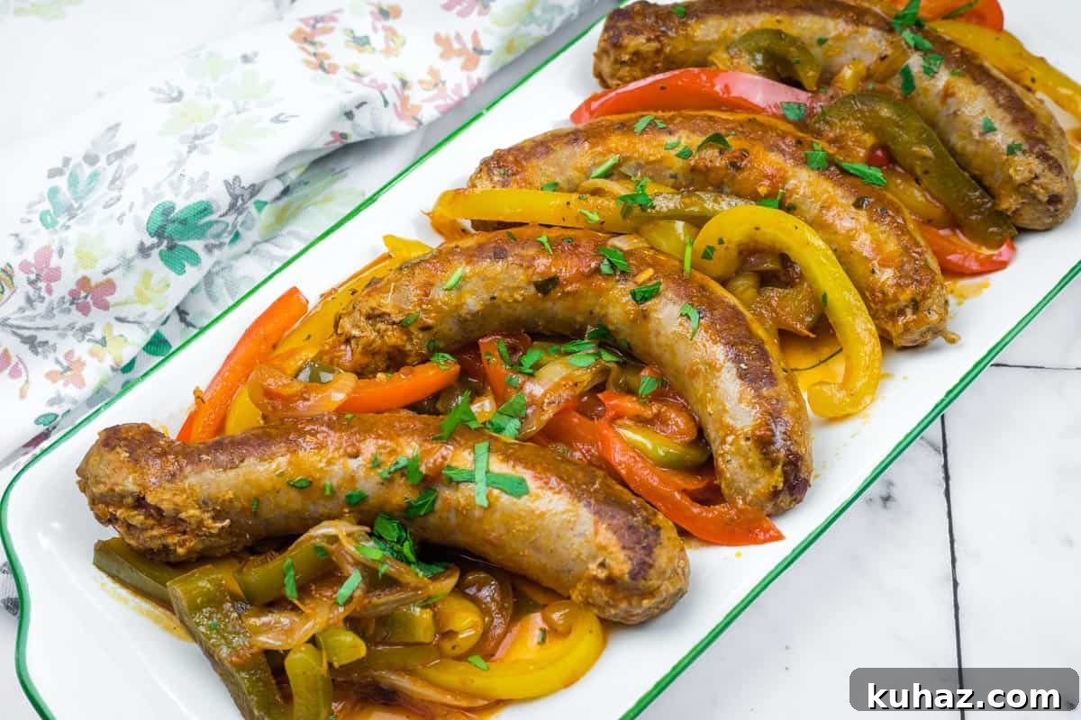 17 Authentic Italian Dinner Recipes Even Nonna Will Love 11 Five cooked Crock Pot Sausage and Peppers served on a white rectangular dish, garnished with chopped herbs.