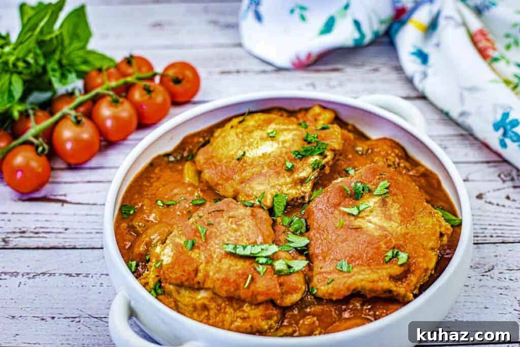 17 Authentic Italian Dinner Recipes Even Nonna Will Love 6 A white dish filled with pieces of Chicken Cacciatore in a red sauce, garnished with chopped herbs.