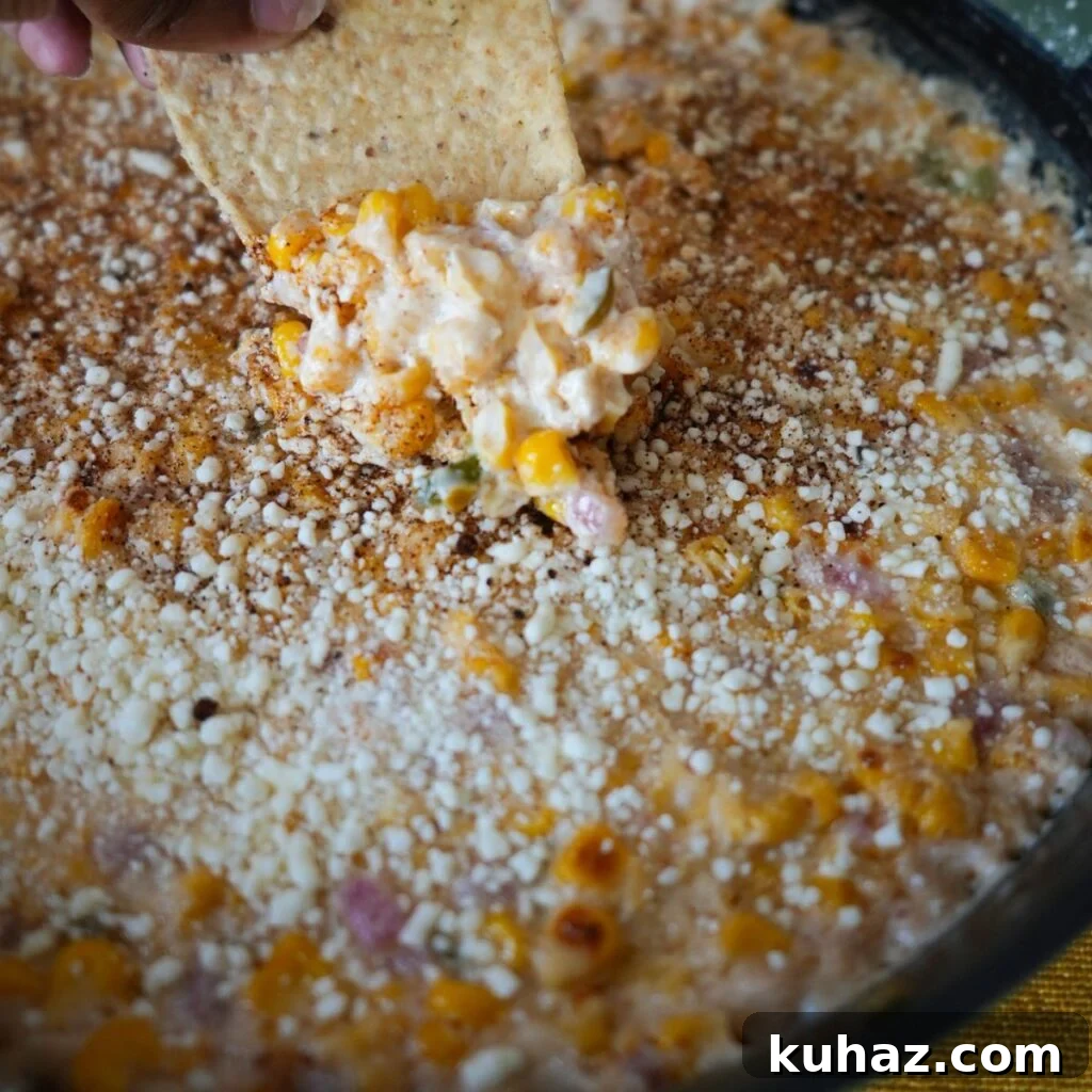 Elote dip being scooped out of the pan.