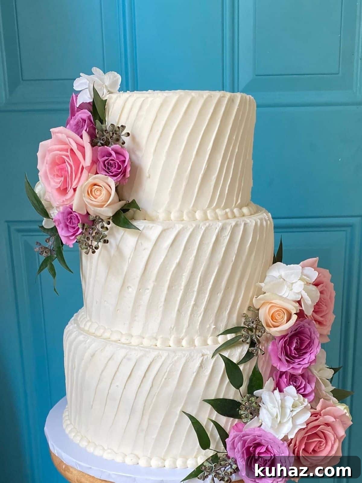 How to Transport a Wedding Cake Without Damage 7 Tips 2 A three-tiered wedding cake with white buttercream and fresh flowers.