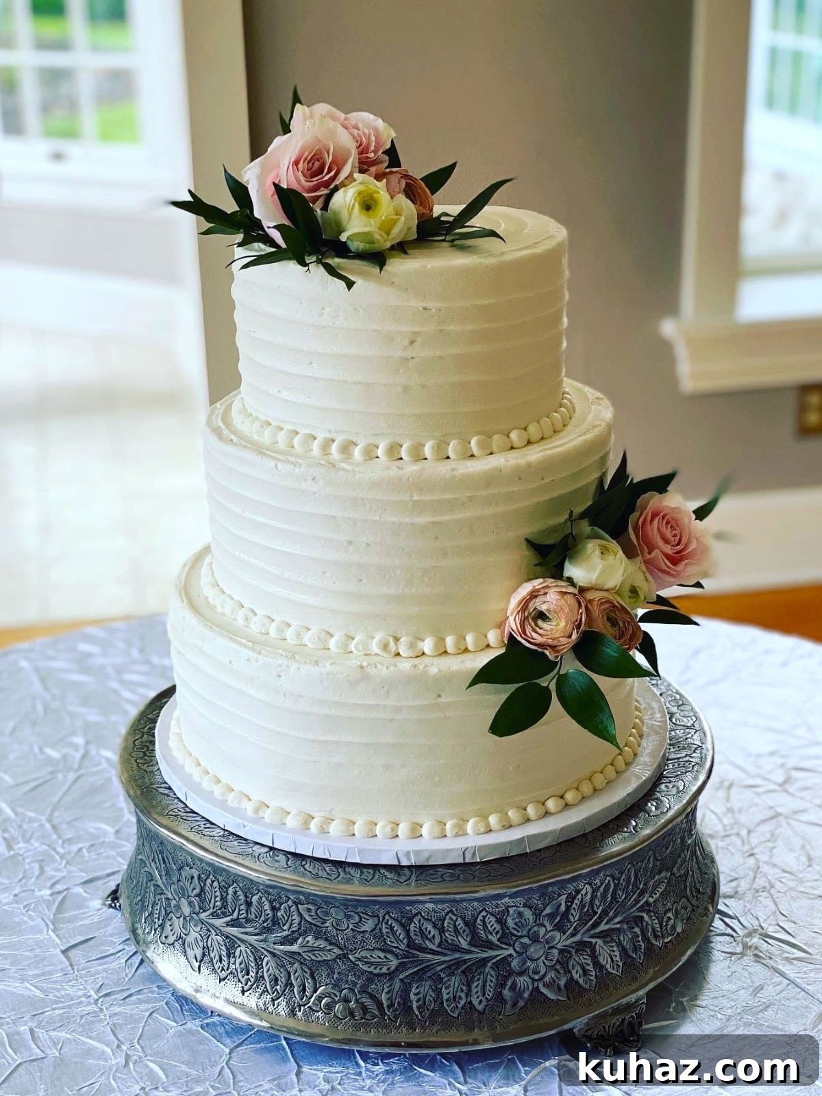 How to Transport a Wedding Cake Without Damage 7 Tips 7 A three-tiered wedding cake that has been transported on a cake drum and then placed on a cake stand at the event venue.