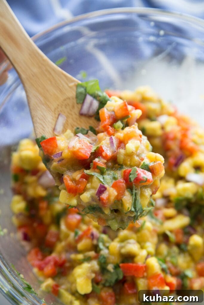 Instant Pot Chicken Carnitas with Avocado Peach Salsa Recipe 5 A close up of avocado peach salsa in a glass bowl on a wooden spoon.