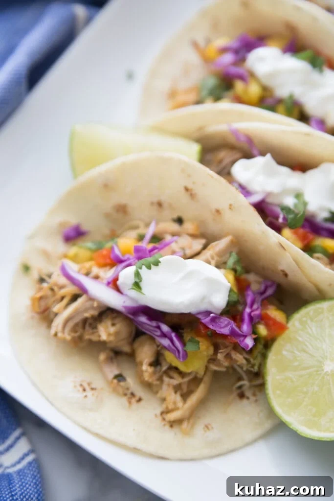 Instant Pot Chicken Carnitas with Avocado Peach Salsa Recipe 6 A close up of a plate of chicken carnitas on corn tortillas and topped with greek yogurt and peach salsa