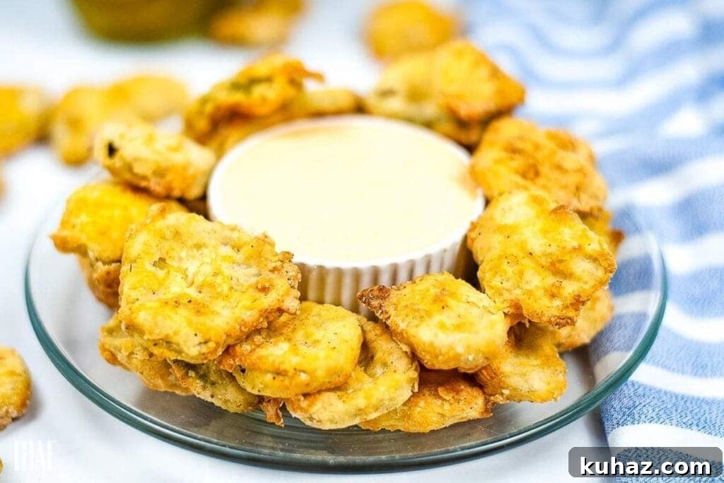Crispy Air Fryer Pickle Chips Recipe 6 Air fryer pickle chips on a glass plate with a bowl of sauce in the middle.