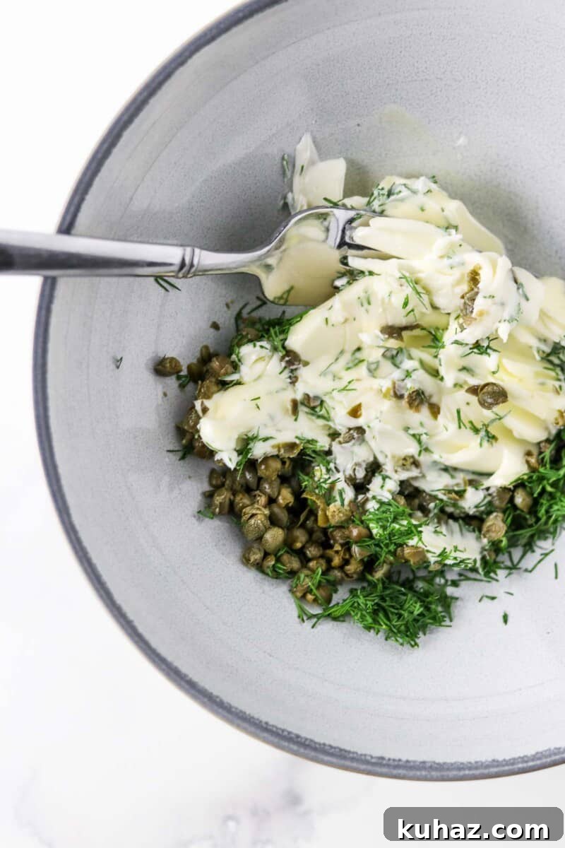 Three-Ingredient Dill and Caper Butter Recipe 4 Butter, dill and capers together in a bowl with a fork.