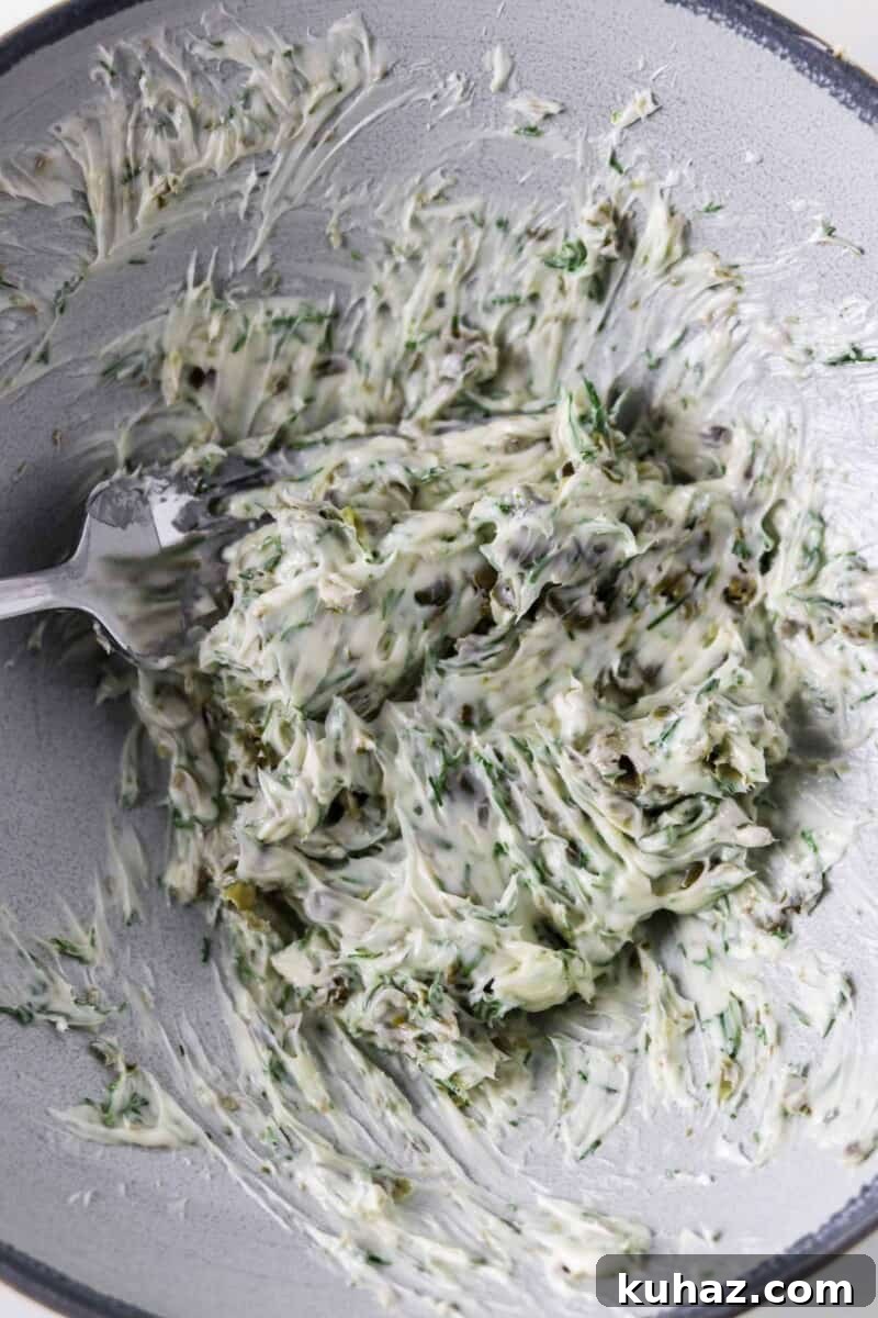 Three-Ingredient Dill and Caper Butter Recipe 5 Dill Caper Butter being stirred with a fork in a bowl.