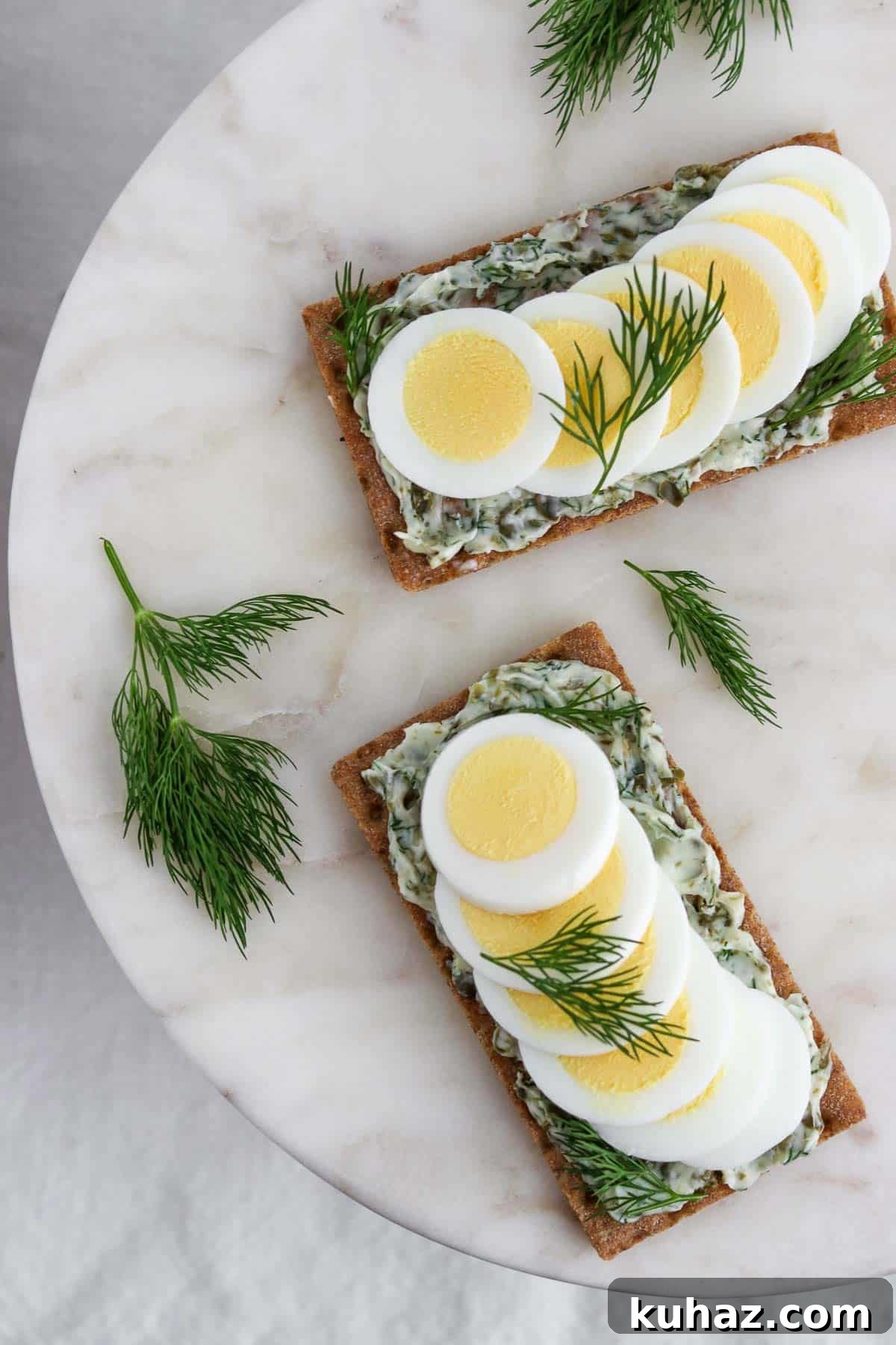 Three-Ingredient Dill and Caper Butter Recipe 6 Overhead view of crispbread spread with dill caper butter and topped with hard-boiled egg and sprigs of dill.