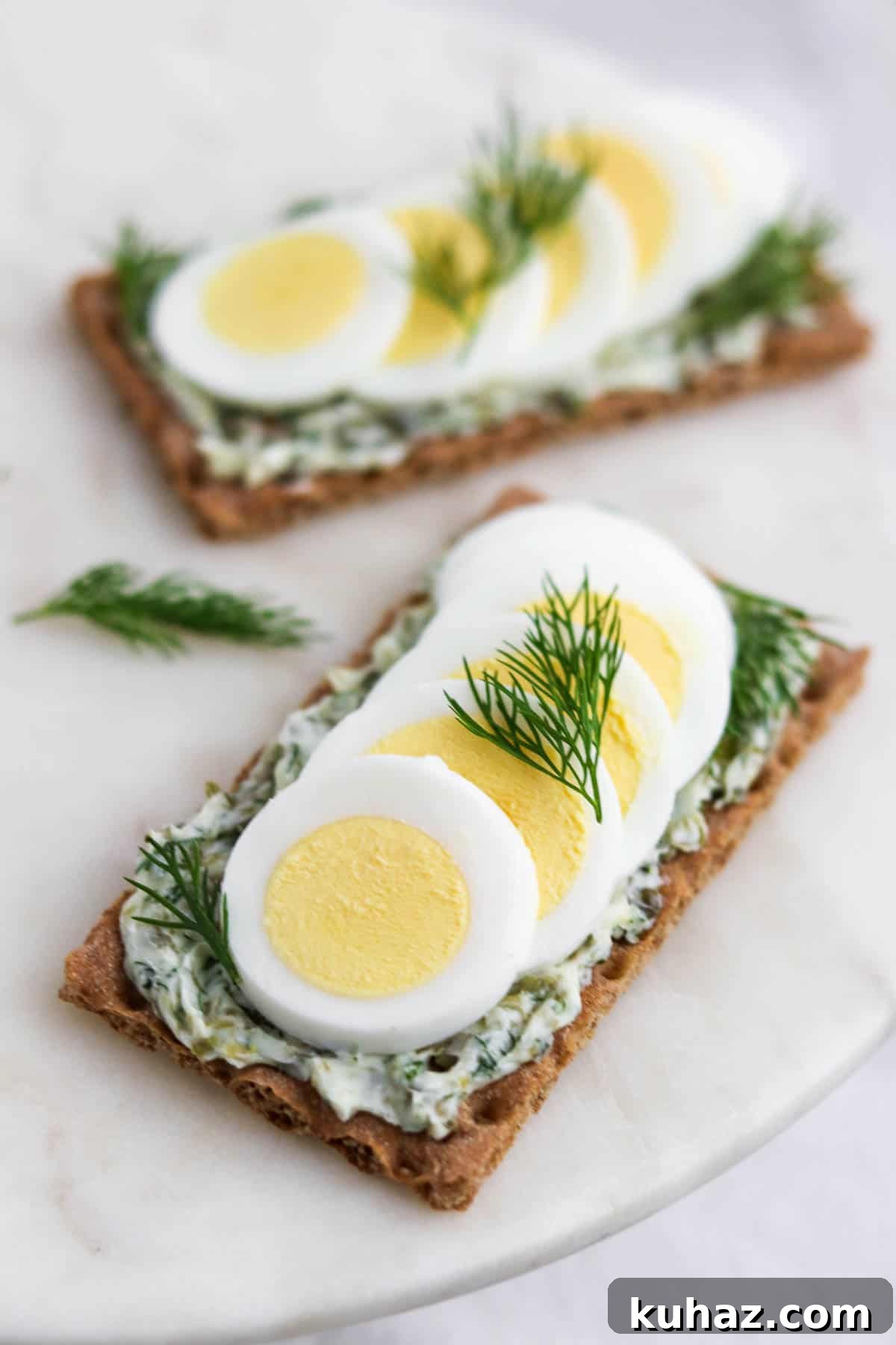 Three-Ingredient Dill and Caper Butter Recipe 8 Crispbread topped with dill caper butter and slices of hard-boiled egg and dill sprigs.
