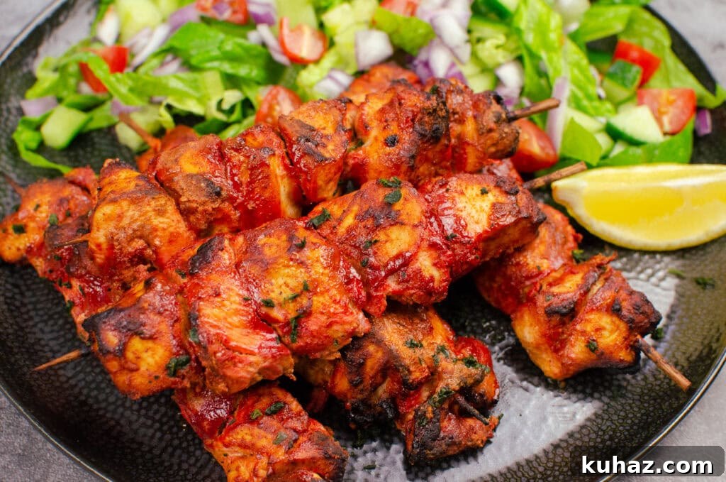 How to Make Authentic Tandoori Chicken Tikka Kebabs 13 Tandoori Chicken Tikka Kebab served with a side salad and a slice of lemon on a black plate