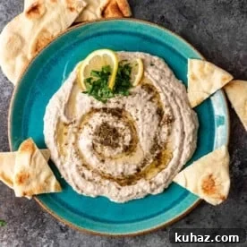 overhead: white bean hummus seasoned with zaatar on aqua blue plate with pita chips